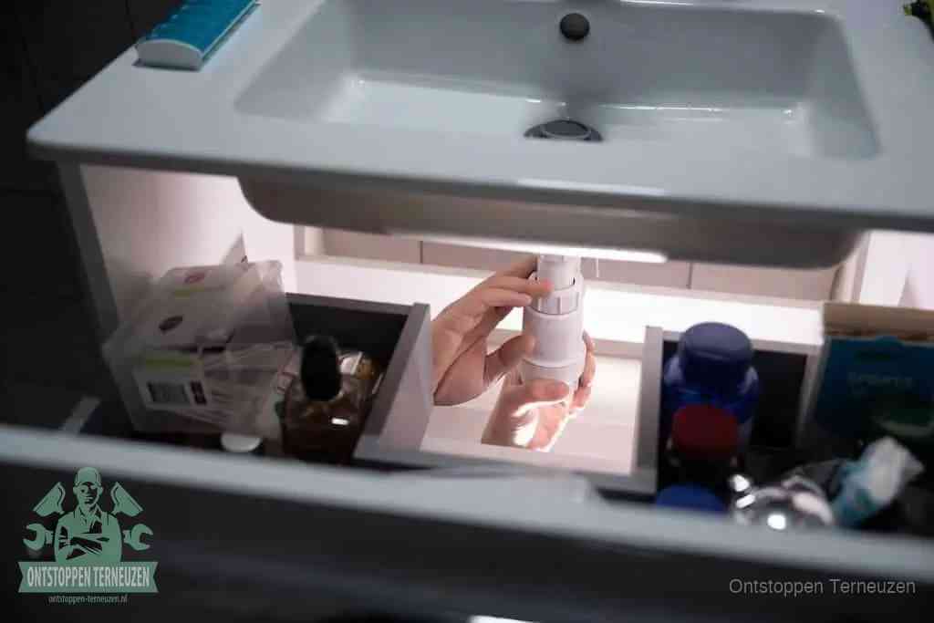 Een pompfles met zeep boven een wastafel, de heet water en afwasmiddel-methode om een vetprop in de afvoer los te maken in Terneuzen