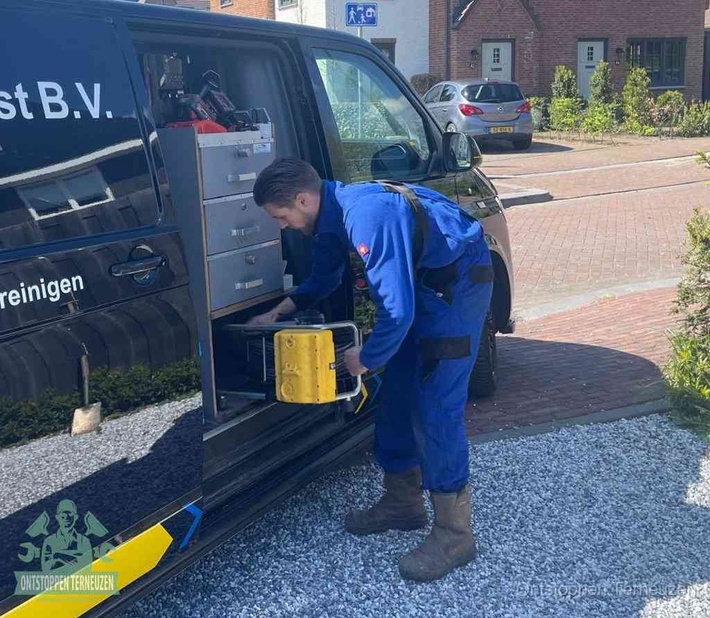 Een monteur pakt buiten op de oprit gereedschap uit de bedrijfsbus, het moment om een professional in te schakelen voor een verstopte afvoer in Terneuzen