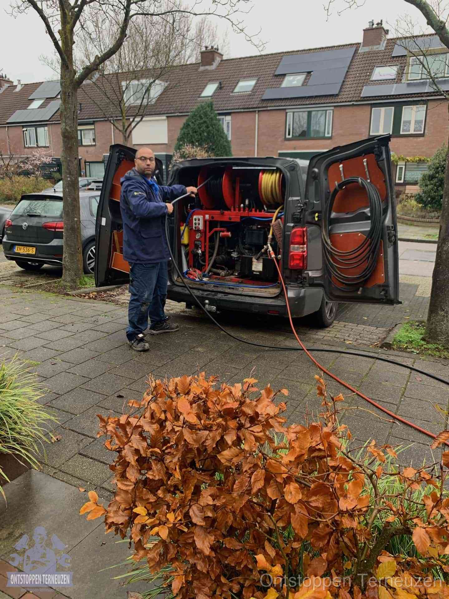Monteur met rioolreinigingsbus levert rioolservice in de wijk in Terneuzen Monteur met rioolreinigingsbus levert rioolservice in de wijk in Terneuzen