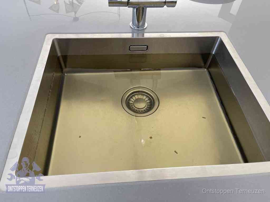 Stilstaand water in een rvs spoelbak dat niet wegloopt, een duidelijk signaal van een gootsteenverstopping in Terneuzen
