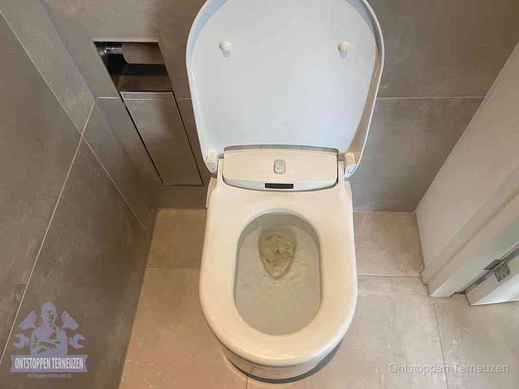 Een wit hangtoilet waarin een prop wc-papier op het water blijft drijven, een duidelijk signaal van een verstopte wc in Terneuzen