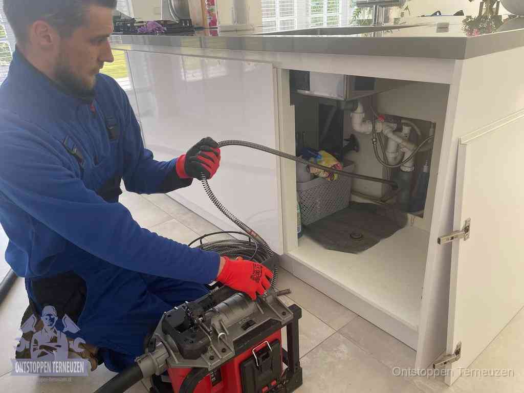 Een monteur reinigt de keukenafvoer grondig met een veermachine om terugkerende gootsteenverstoppingen te voorkomen in Terneuzen Een monteur reinigt de keukenafvoer grondig met een veermachine om terugkerende gootsteenverstoppingen te voorkomen in Terneuzen