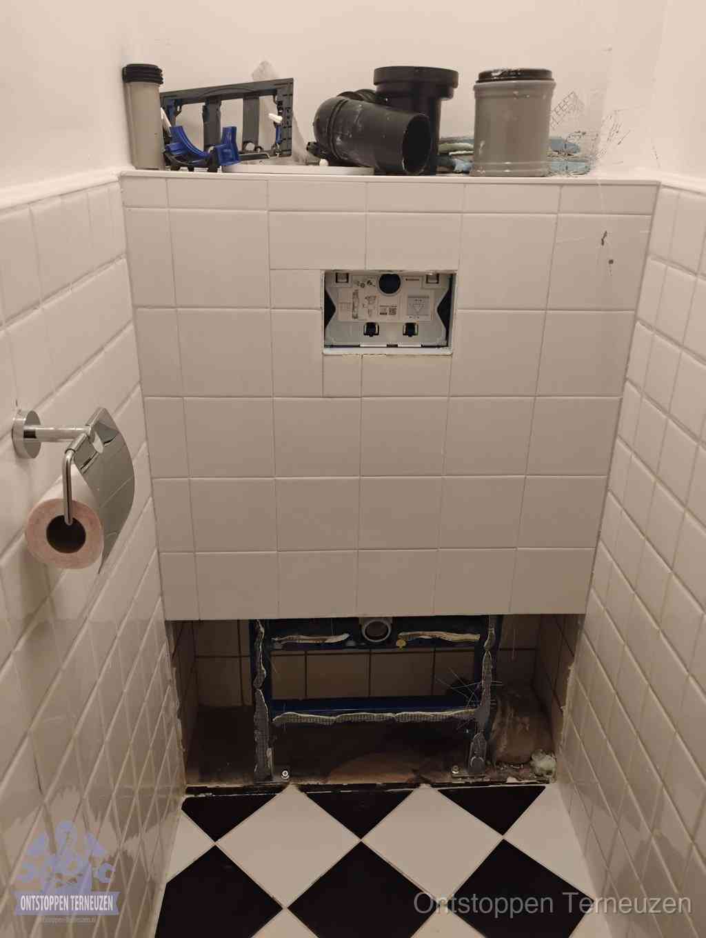 Een toiletruimte waar het hangtoilet en de inbouwreservoir-onderdelen zijn vrijgelegd voor onderhoud, periodiek nazicht voorkomt een wc-verstopping in Terneuzen Een toiletruimte waar het hangtoilet en de inbouwreservoir-onderdelen zijn vrijgelegd voor onderhoud, periodiek nazicht voorkomt een wc-verstopping in Terneuzen