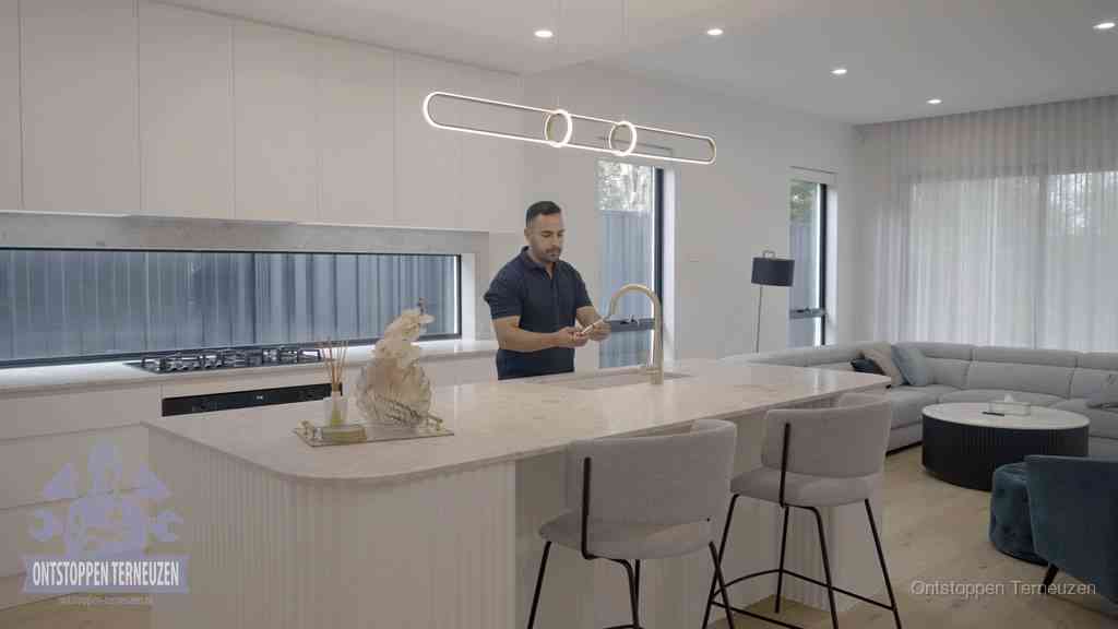 Een bewoner bij de keukenspoelbak die zelf aan de slag gaat met een verstopte gootsteen in Terneuzen Een bewoner bij de keukenspoelbak die zelf aan de slag gaat met een verstopte gootsteen in Terneuzen